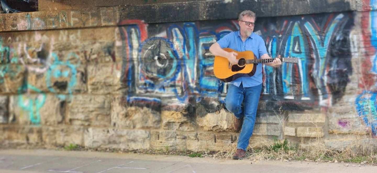 Photo of Nick Stika holding a guitar
