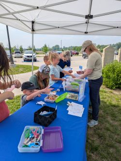 image of children standing under a pop up tent learning about nature with Linn County Conservation