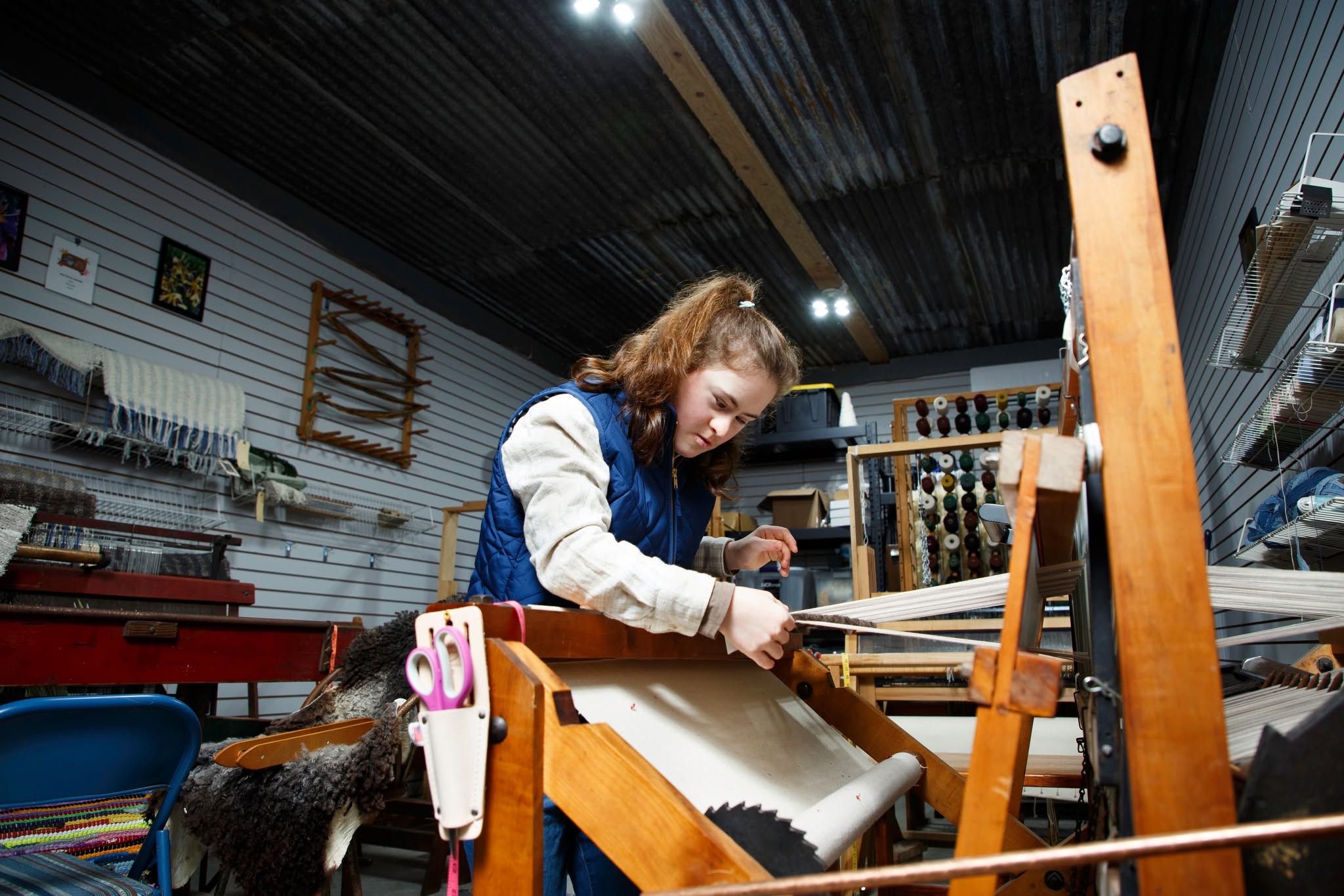 image of a girl operating a weaving loom at Wapsi Weaving in Central City Iowa